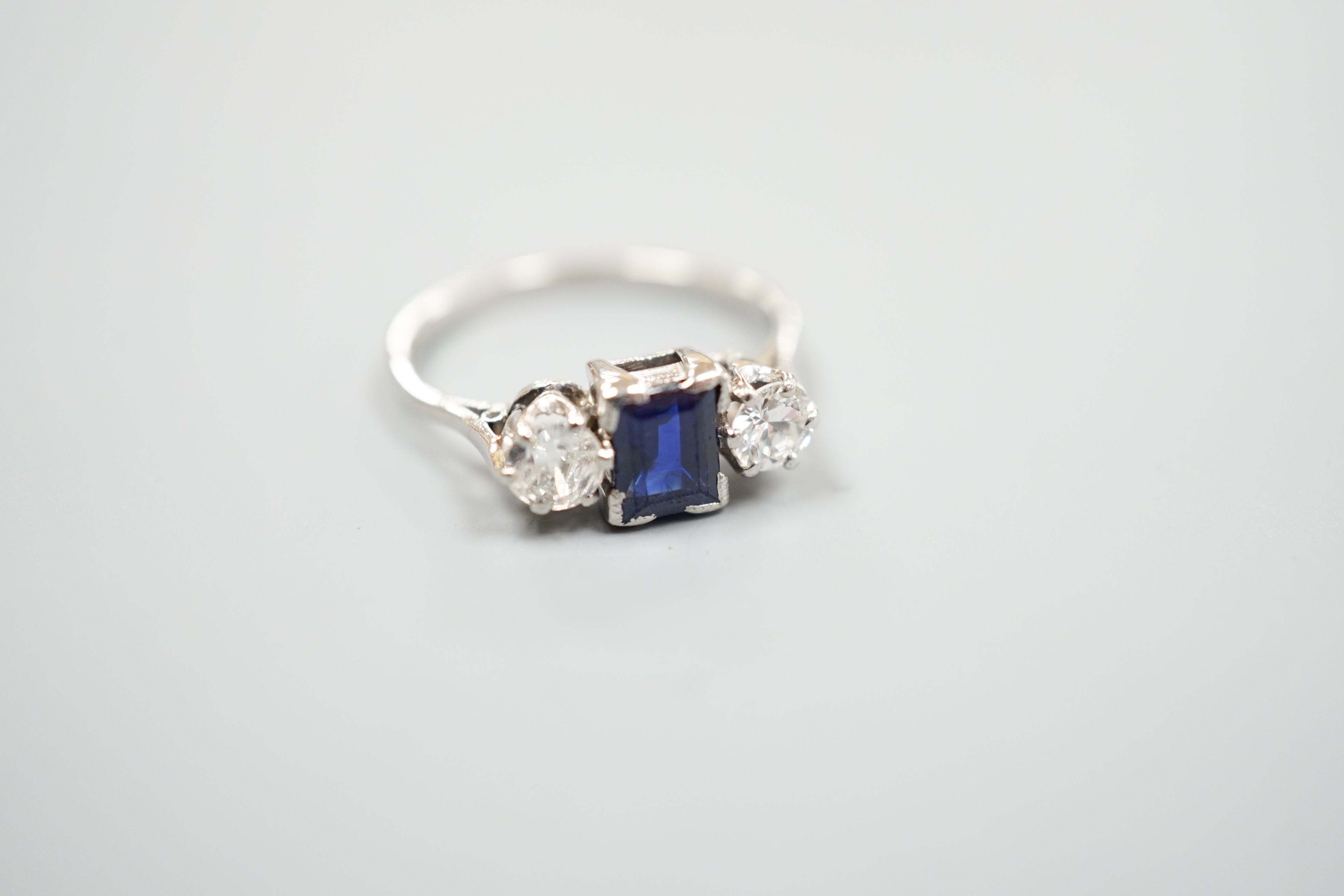 A white metal (stamped plat), sapphire and diamond set three stone ring, size K, gross weight 3.6 grams.